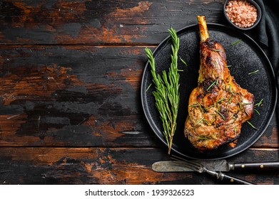 Baked lamb, sheep leg with rosemary. Dark wooden background. Top view. Copy space