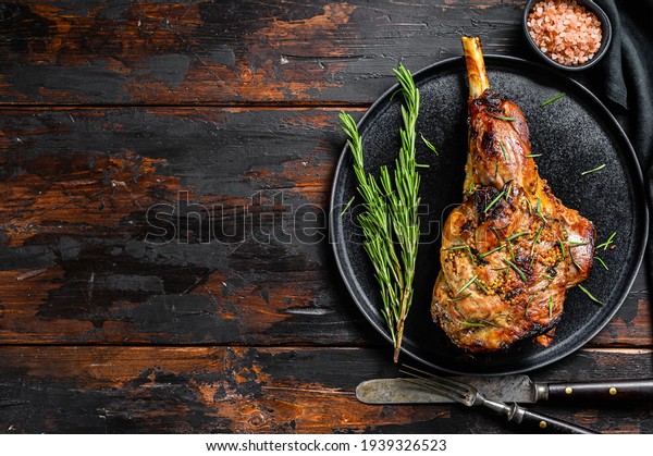 Baked lamb, sheep leg with rosemary. Dark\
wooden background. Top view. Copy\
space