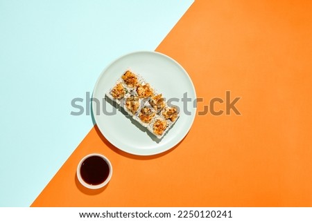 Baked maki sushi in ceramic plate on coloured background. Sushi roll with shrimp tartare in trendy style on orange and blue colour backdrop. Maki roll with hard shadows in minimal style Stockfoto © 