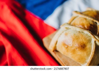 Baked meat chilean empanadas on the chilean flag. Copy space. Independence day concept. Selective focus - Shutterstock ID 2176887807