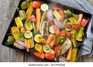 Baked mixed colorful vegetables on a baking sheet  just coming steaming out of the oven - Powered by Shutterstock