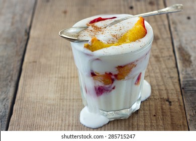 baked peach and vanila ice cream in a glass on wooden background