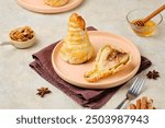 Baked pears in puff pastry with nut filling, drizzled with honey, on a plate on a light concrete background. Pear recipes. Thanksgiving Day.