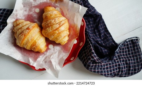 Baked Plain Butter Croissants Served In Red Dessert Plate With Food Grade Oil Absorbing Paper On White Painted Wooden Table With Blue Plaid Or Tartan Cloth Napkin. (top View, Selective Focus)