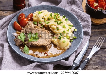 Baked pork with mashed potatoes and green scallion on plate, close-up