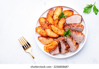 Baked pork tenderloin with quince or apple slices served on plate. White table background, top view - Shutterstock ID 2236858687