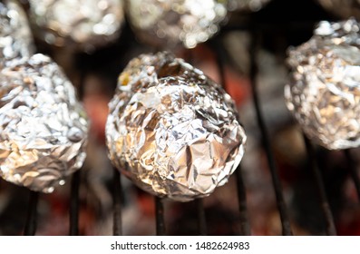 Baked Potato In Aluminum Foil On Barbecue, Cooking Potatoes On BBQ