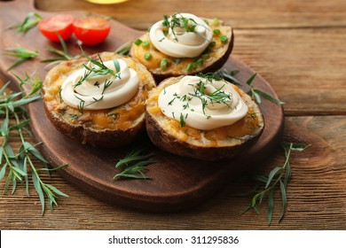 Baked potato with mayonnaise and herbs on wooden cutting board, closeup - Powered by Shutterstock