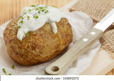 Baked Potato With Sour Cream On Wooden Board