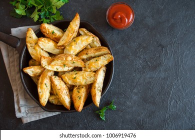 Baked potato wedges with cheese and herbs and tomato sauce on black background - homemade organic vegetable vegan vegetarian potato wedges snack food meal.