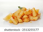 Baked potato wedges with olive oil,origanum,thyme and lemon photographed on white reflective surface.

