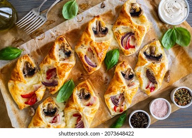 Baked puff pastry with mozzarella, white mushrooms and red bell pepper on baking paper 