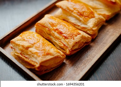 Baked puff pastry with toppings. Puffs with cheese on a wooden tray. - Shutterstock ID 1694356201