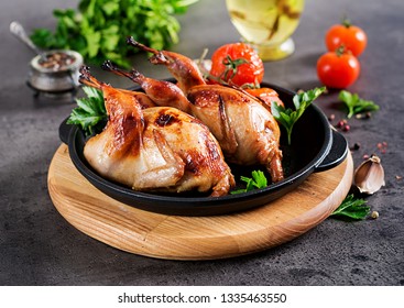 Baked quails in pan on a dark background