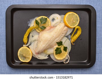 Baked RedFish Lemon And Onions Slices, Fresh Parsley, Hot Peppers In Pan On Blue Table Cloth