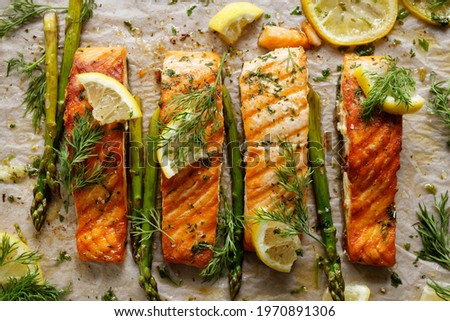 Baked salmon with aromatic herbs and lemon on baking paper top view