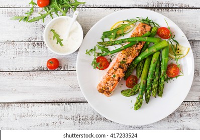 Baked salmon garnished with asparagus and tomatoes with herbs.Top view