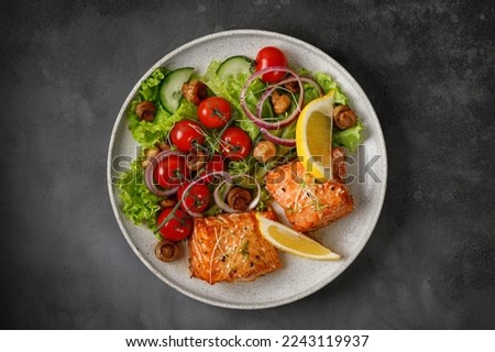 Baked Salmon with green fresh vegetable salad, tomatoes cherry, onion on ceramic plate. Concept keto diet healthy food. Dinner idea. Top view.