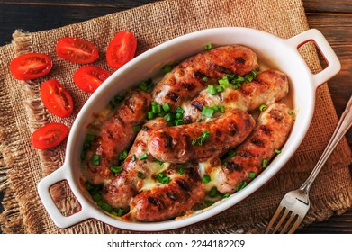 Baked sausages topped with cheese and green onions - Shutterstock ID 2244182209