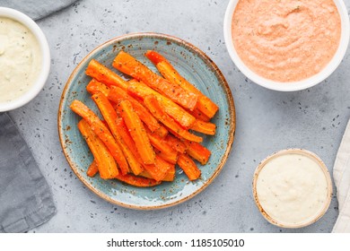 Baked Season Carrot Sticks With Sauce And Hummus. Vegetarian Healthy Food. Flat Lay, Top View.