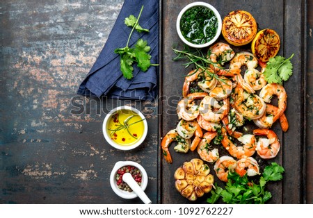 Baked shrimps prawns on cast iron grill board, top view. Dark background.