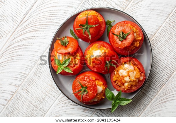 Baked stuffed tomatoes with rice and cheese. Top\
view. White table.