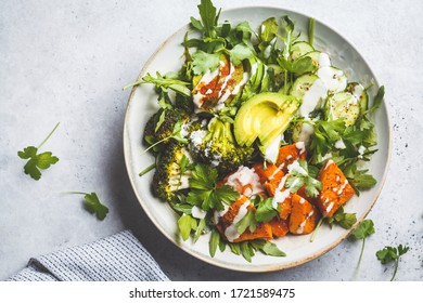 Baked Sweet Potato, Broccoli And Avocado Salad Bowl With Tahini Dressing.