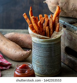 Baked Sweet Potato Fries And Ketchup. Whole Sweet Potatoes In The Background.