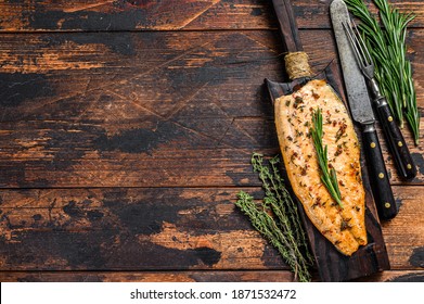 Baked trout fillet on a cutting board. Dark wooden background. Top view. Copy space
