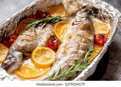 baked trout with lemon, orange, spices on a stone background