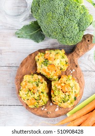 Baked vegetable patties with carrots, broccoli and cheese on dark wooden serving board. Vertical image