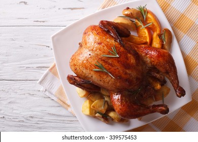 Baked Whole Chicken With Oranges And Potatoes On A Plate. Horizontal View From Above
