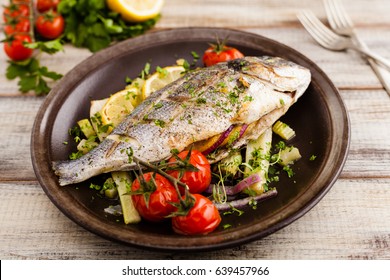 Baked Whole Fish, Served With Roasted Vegetables And Lemon. Front View.