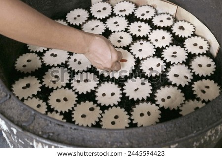 Baker Adding Raisins on the Mid-baked Batter of Portuguese-Siamese Kudeejeen Cupcakes or Khanom Farang Kudeejeen
