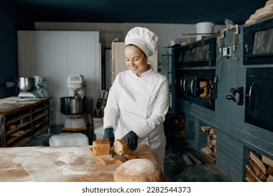 Baker chef holding knife and cutting fresh bread on wooden table - Powered by Shutterstock