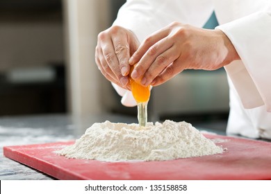 A baker cracking an egg into a pile of flour. - Powered by Shutterstock