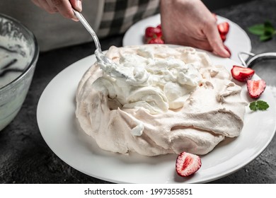 Baker Decorating Fresh Delicious Homemade Pavlova Cake Meringue Cake With Whipped Cream And Strawberries. Culinary, Bakery, Food And People Concept