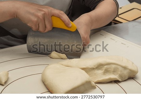 Baker Divides Dough With Scraper