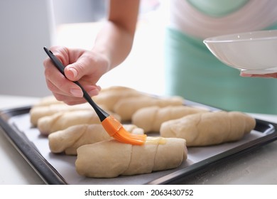 The baker greases the buns with an egg before baking - Powered by Shutterstock