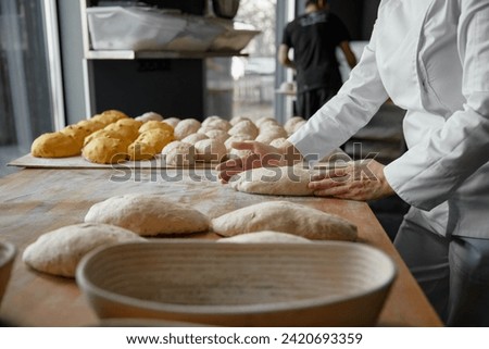Baker hands preparing formed bread dough for proofing