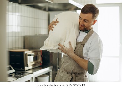 Baker holding big flour bag at the kitchen in bakery house