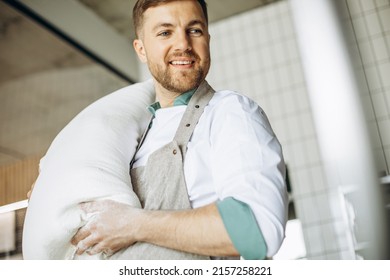 Baker Holding Big Flour Bag At The Kitchen In Bakery House