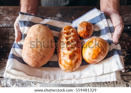 Baker holding fresh hot bread close-up. Warm fresh buns on kitchen towel in man hands. Homemade bakery, soft tack preparing, kitchen concept