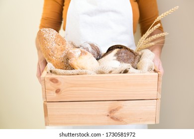 Baker Holding Wooden Box With Freshly Baked Bread And Wheat Ears. Closeup Of Person Holding Food. Baking Or Traditional Bread Concept