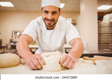 Baker kneading dough at a counter in a commercial kitchen - Powered by Shutterstock