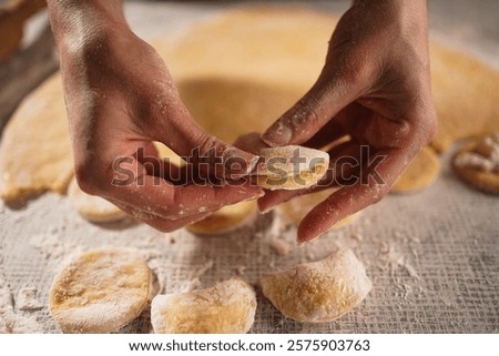 Baker makes dumplings with cottage cheese from raw dough with filling, close-up of hands. Copy space