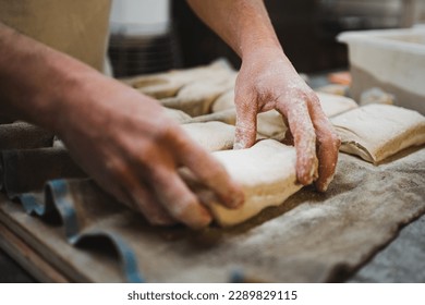 Baker man placing bread dough on couche cloth to rest. Artisan bakery. - Powered by Shutterstock