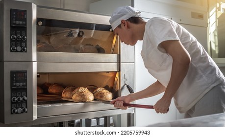 The baker is a man in the process of baking bread. Production of bakery products as a small business. - Powered by Shutterstock