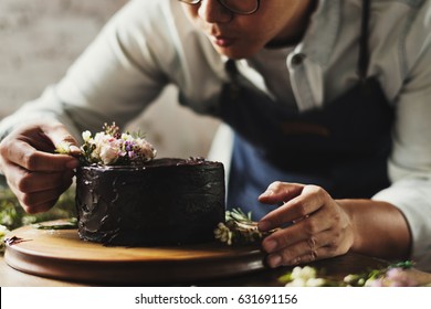 Baker Man Using Flowers Decorating Chocolate Cake - Powered by Shutterstock