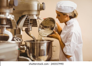 Baker pouring flour into large mixer in a commercial kitchen - Powered by Shutterstock